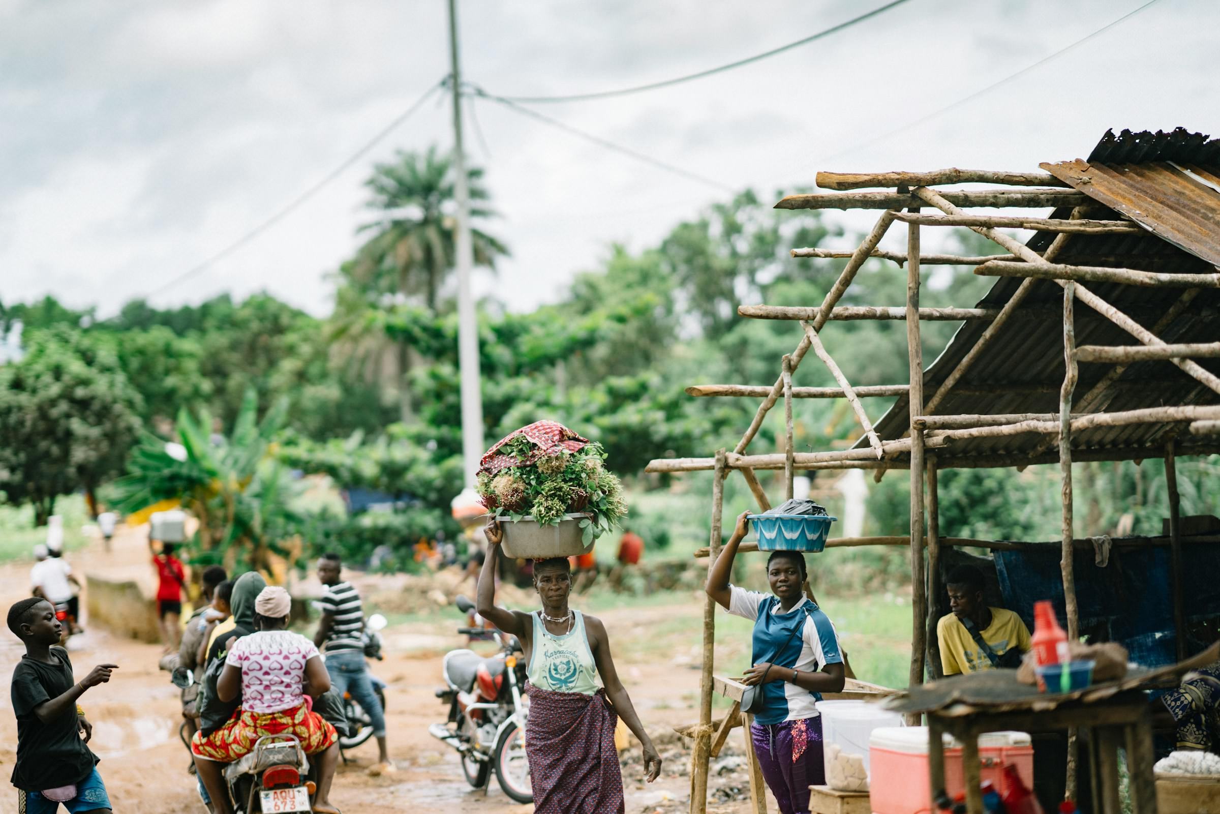 Women carrying goods on their heads through a market street in Sierra Leone